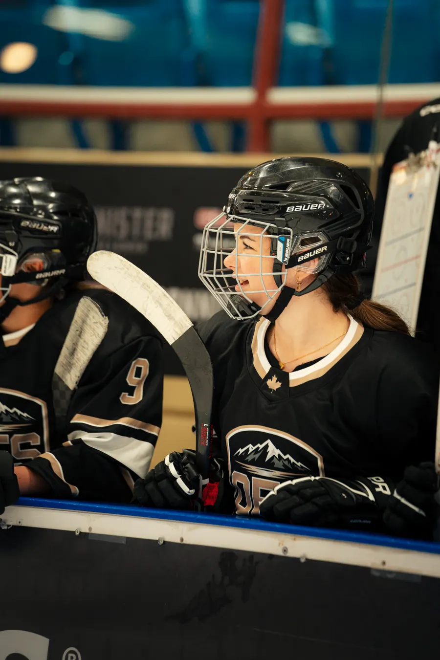 Smiling OFS player on the bench with her stick