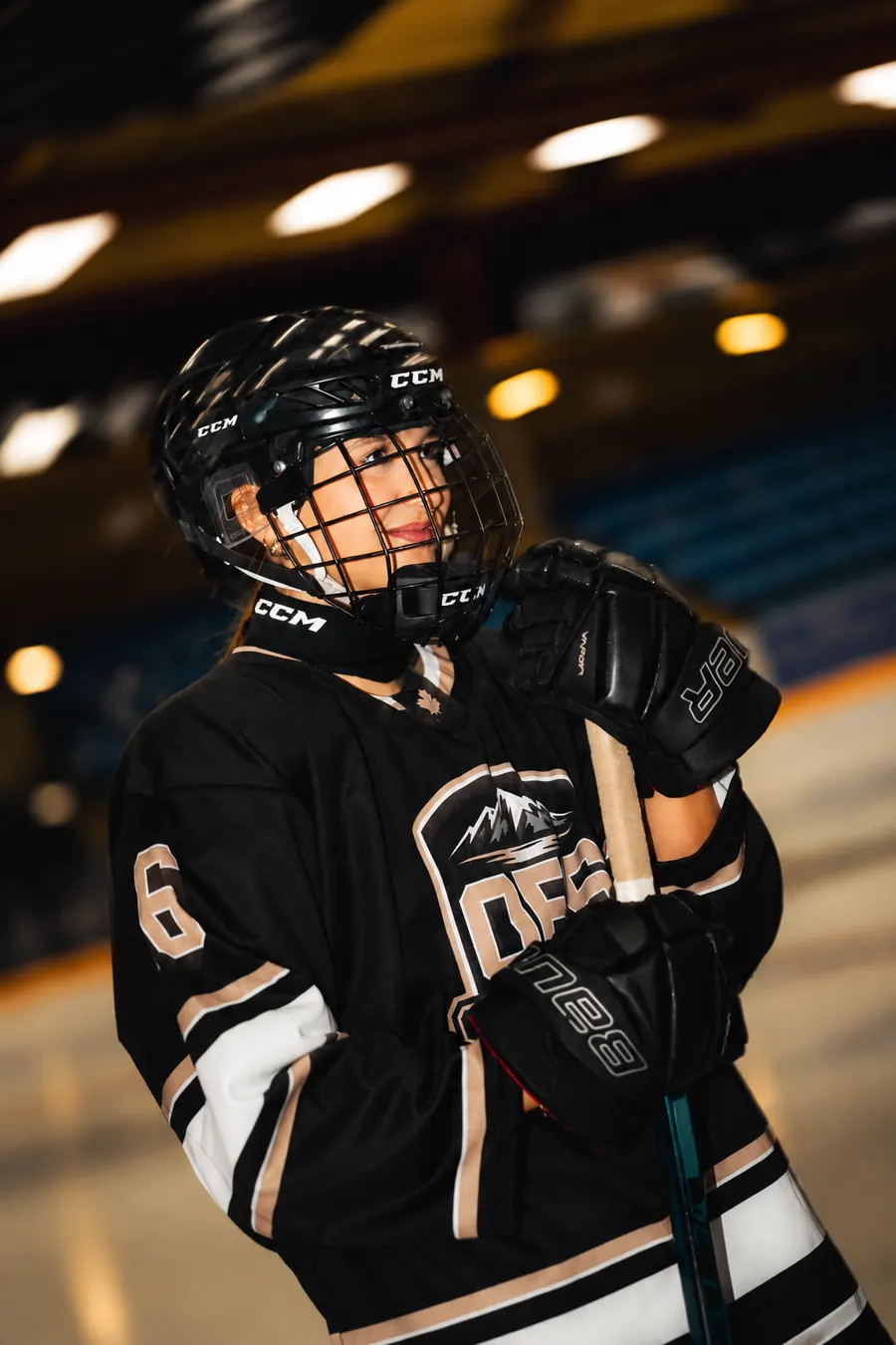 Smiling OFS player holding her stick in the number 6 jersey