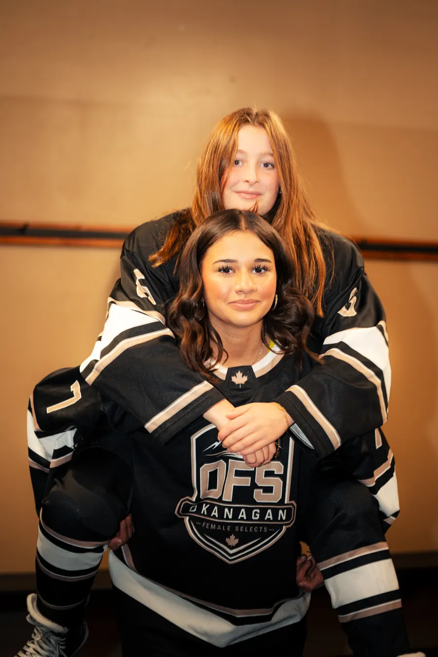 Two OFS teammates in team jerseys, one on the other's back