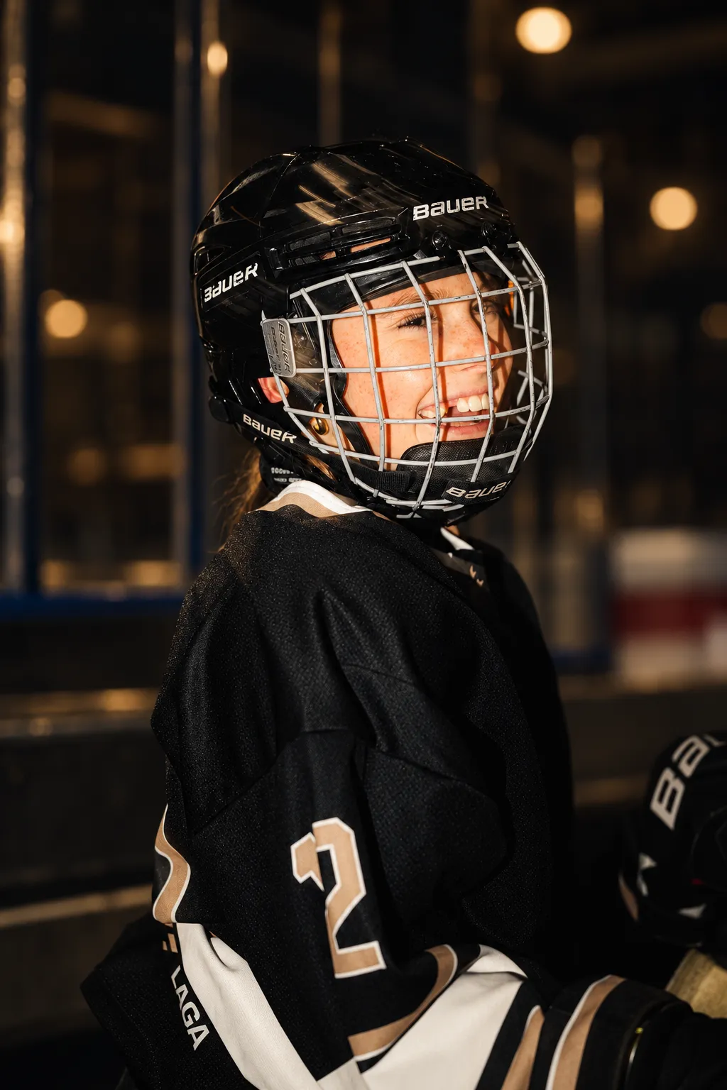 Smiling OFS player in her helmet and number 2 jersey on the bench